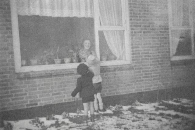 In korte broek kijken de broertjes Hans en Leo Engels in restanten sneeuw bij buurvrouw Steverink naar binnen.